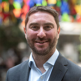 person with short hair and a beard smiling at the camera