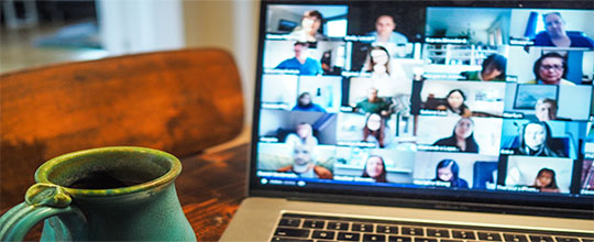 cup in front of a laptop showing a virtual meeting