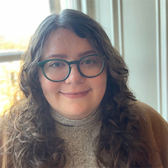 person with long wavy hair and glasses smiling