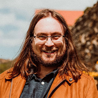 person with long hair sand glasses smiling at the camera