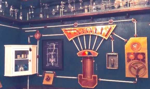 Image from Room Escape Artist's review of the Edison Escape Room in SF showing pipes, turning handles and a cupboard with bottles