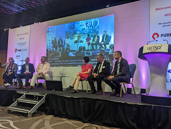 panel of 6 people sat on stage in a conference setting