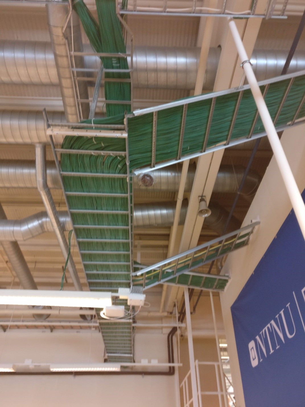 Photograph of cabling and pipes on the ceiling of the NTNU Eksamen (exam) building 