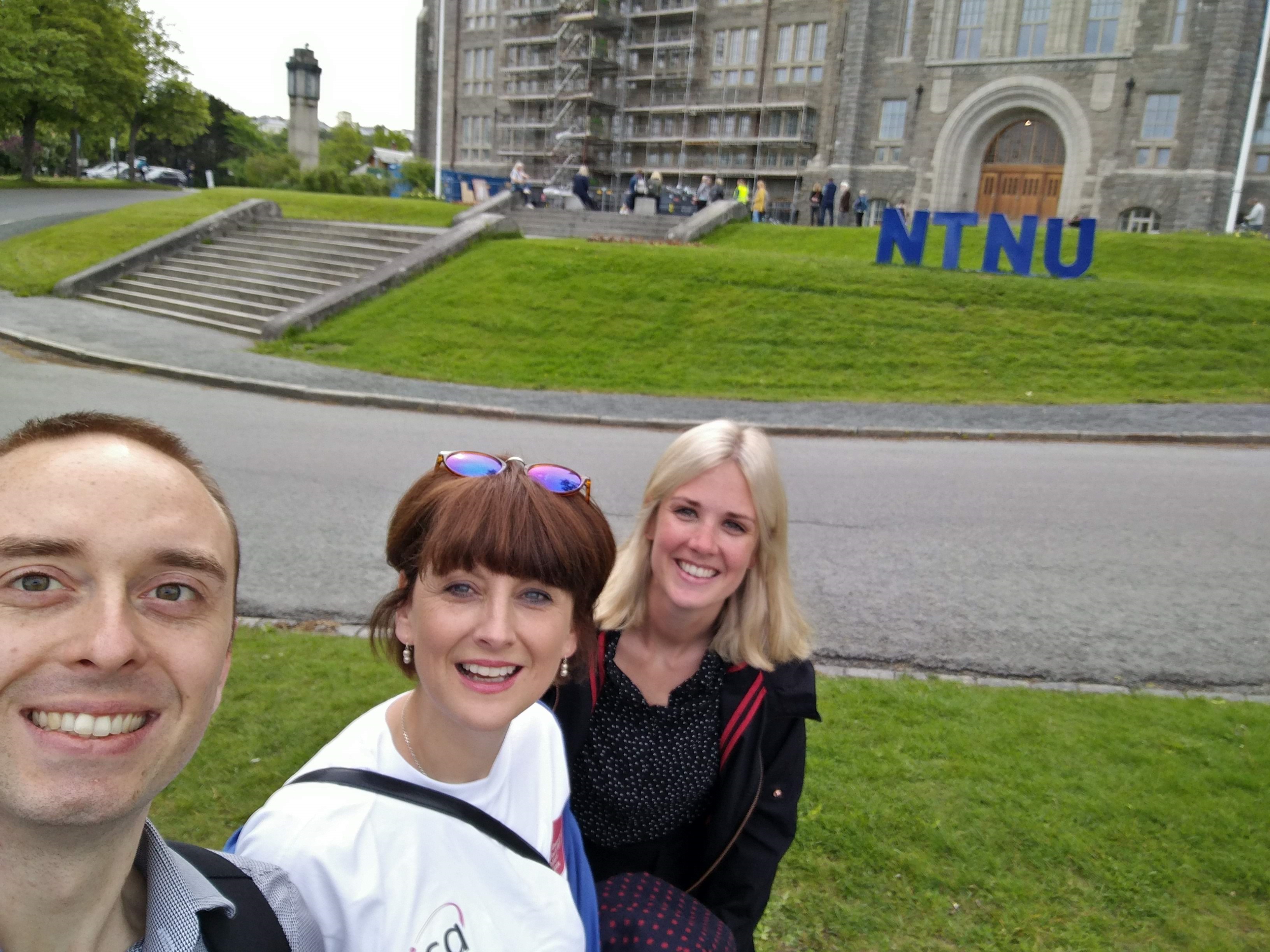 Colour photograph of bursary winners Sam Harrow, Elizabeth Griffiths and Samantha Chester in front of an NTNU building 